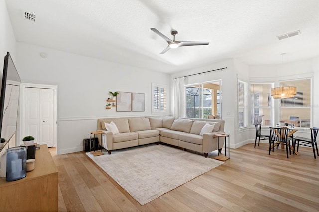 living room featuring a textured ceiling, light wood-type flooring, and ceiling fan