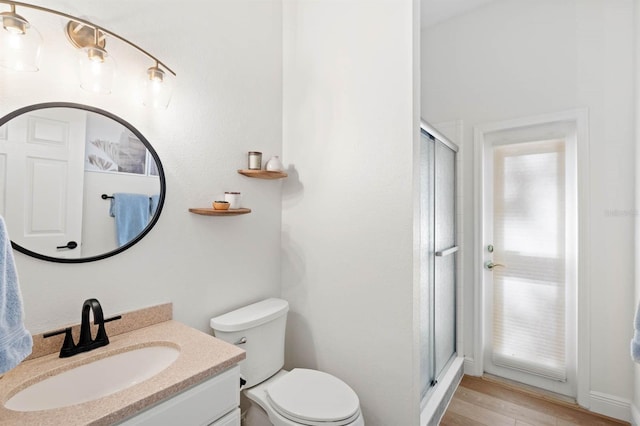 bathroom featuring vanity, toilet, wood-type flooring, and walk in shower