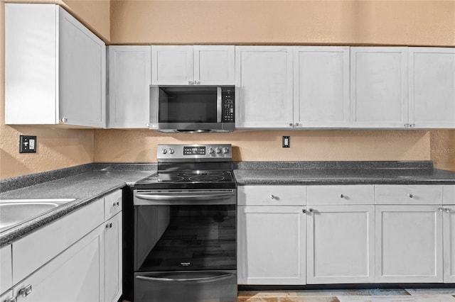 kitchen with appliances with stainless steel finishes, white cabinetry, and sink