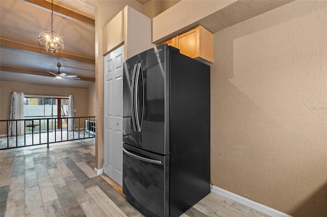 kitchen featuring black refrigerator, light wood-type flooring, beamed ceiling, and ceiling fan with notable chandelier