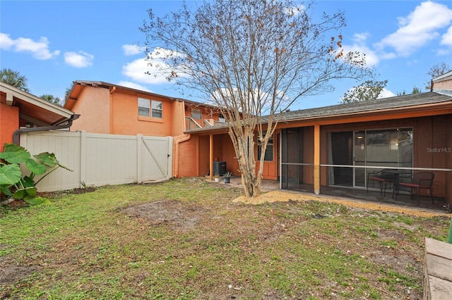 rear view of property with a lawn, central AC, a patio area, and a sunroom