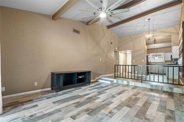 unfurnished living room featuring ceiling fan with notable chandelier, wood-type flooring, and lofted ceiling with beams