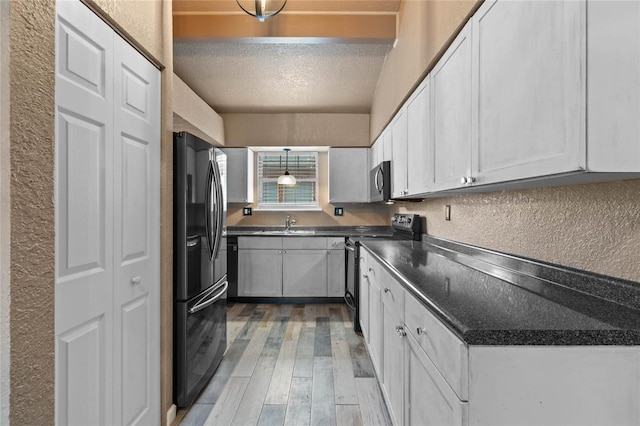 kitchen with sink, light hardwood / wood-style flooring, a textured ceiling, stainless steel appliances, and white cabinets