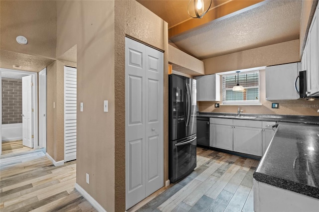 kitchen with light wood-type flooring, white cabinetry, and black appliances