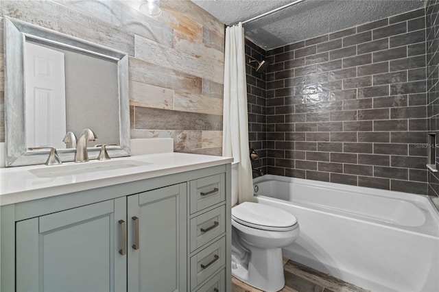 full bathroom featuring shower / bath combo with shower curtain, a textured ceiling, toilet, and vanity