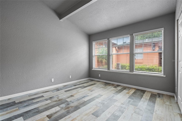 unfurnished room featuring light hardwood / wood-style floors, a textured ceiling, and lofted ceiling with beams