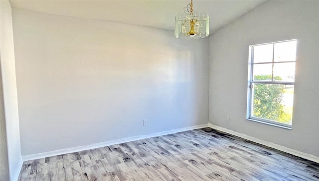 unfurnished room featuring a chandelier, light hardwood / wood-style flooring, a wealth of natural light, and lofted ceiling