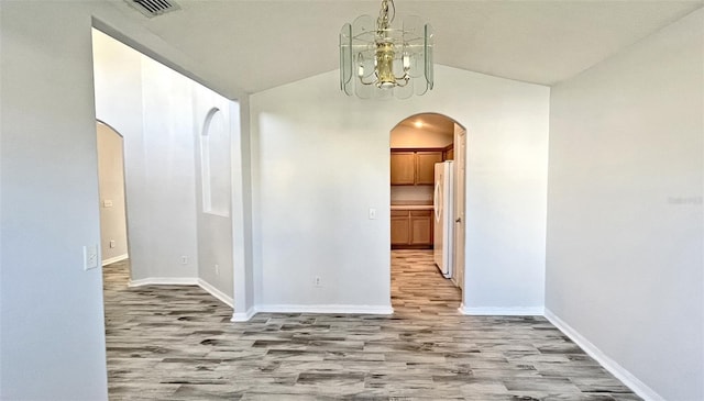 hallway with lofted ceiling, light hardwood / wood-style flooring, and a chandelier