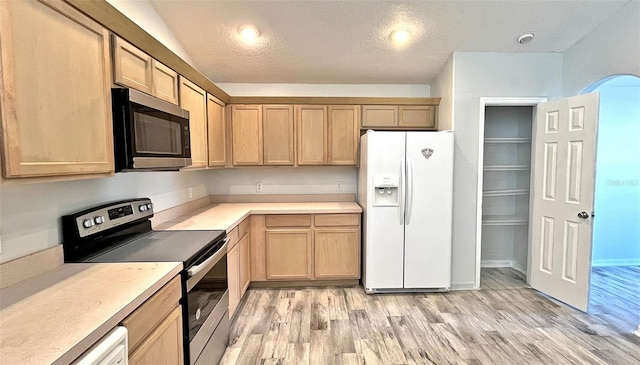 kitchen with light brown cabinetry, a textured ceiling, and appliances with stainless steel finishes