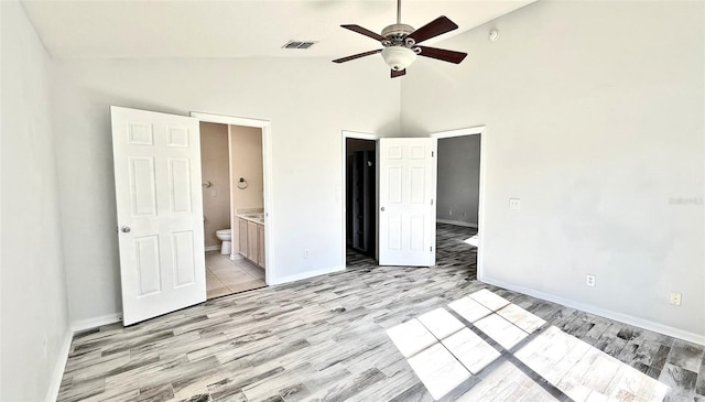 unfurnished bedroom with connected bathroom, ceiling fan, high vaulted ceiling, and light wood-type flooring