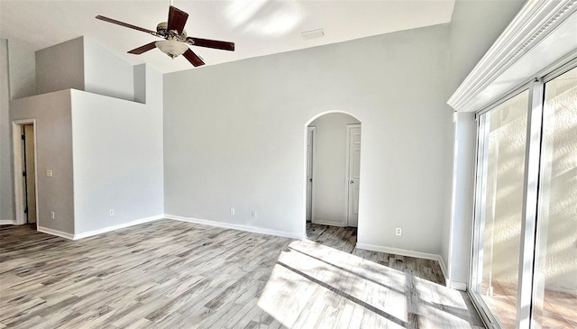 empty room featuring ceiling fan, a high ceiling, and light wood-type flooring