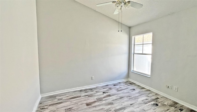 empty room featuring a textured ceiling, light hardwood / wood-style flooring, vaulted ceiling, and ceiling fan