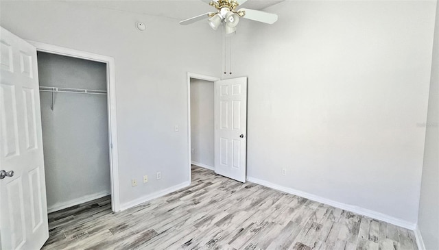 unfurnished bedroom with a high ceiling, light wood-type flooring, a closet, and ceiling fan