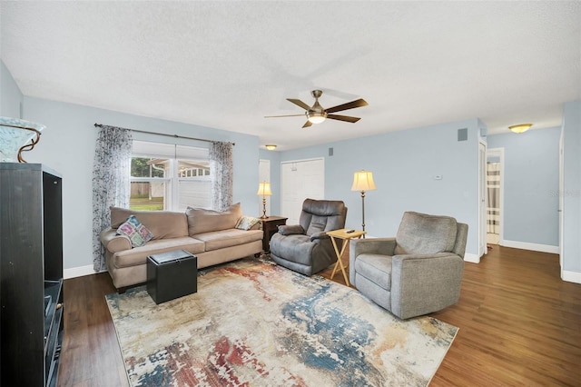 living room featuring ceiling fan, a textured ceiling, and dark hardwood / wood-style flooring