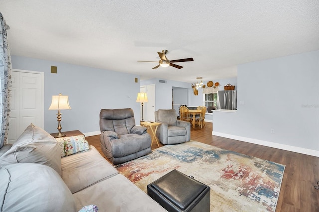 living room featuring ceiling fan, dark hardwood / wood-style floors, and a textured ceiling