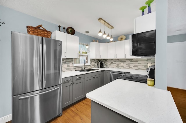 kitchen with sink, gray cabinetry, appliances with stainless steel finishes, pendant lighting, and white cabinets