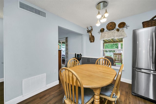 dining space featuring dark wood-type flooring and a textured ceiling