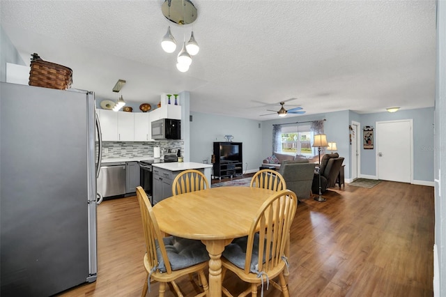 dining area with hardwood / wood-style floors, a textured ceiling, and ceiling fan