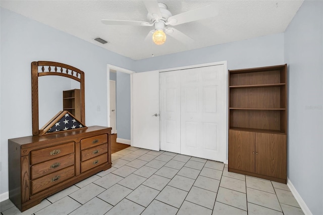 bedroom with light tile patterned floors, a textured ceiling, a closet, and ceiling fan