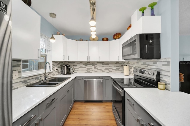 kitchen with pendant lighting, sink, gray cabinets, stainless steel appliances, and white cabinets