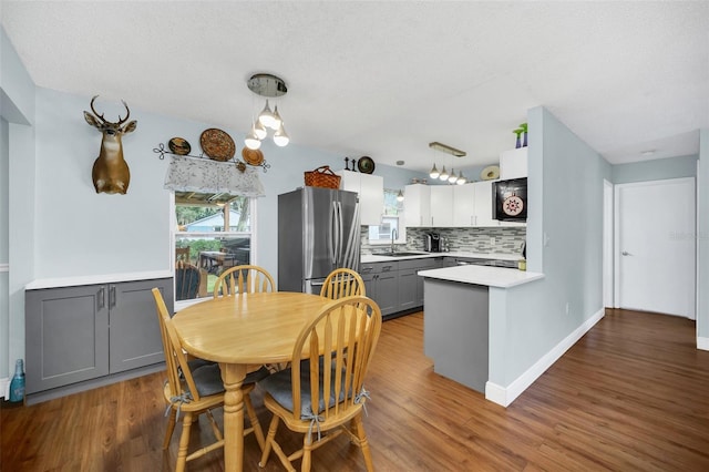 dining space with wood-type flooring, sink, and a textured ceiling