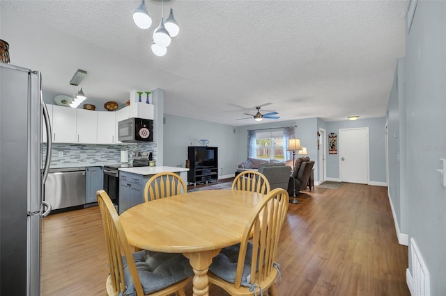 dining area with ceiling fan, light hardwood / wood-style floors, and a textured ceiling