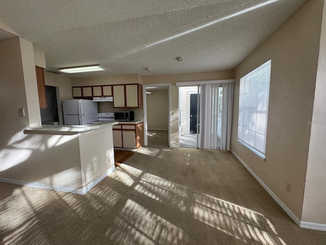 kitchen with white refrigerator, stove, carpet floors, and a textured ceiling