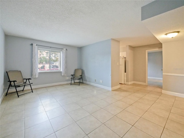 tiled empty room featuring a textured ceiling