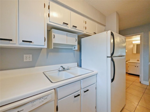 kitchen featuring sink, white appliances, light tile patterned floors, white cabinetry, and a textured ceiling