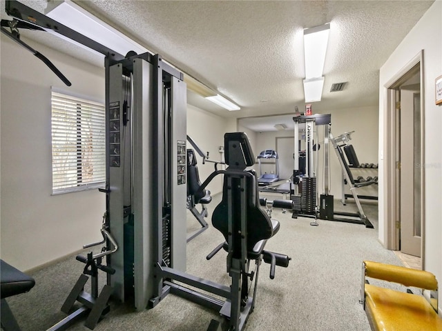 exercise room featuring carpet floors and a textured ceiling