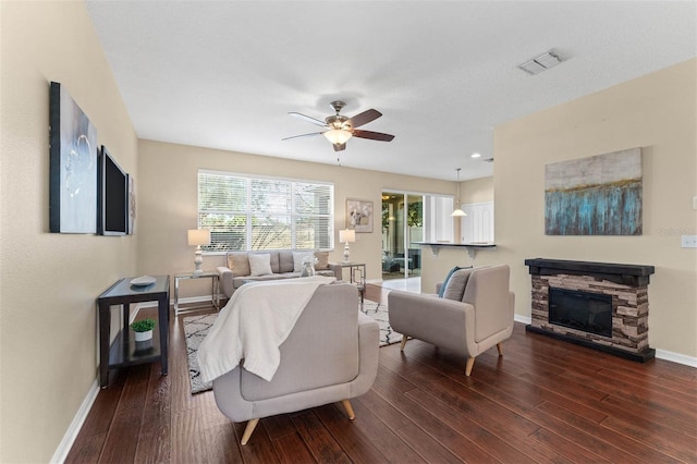 living room featuring a fireplace, dark wood-type flooring, and ceiling fan