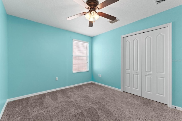 unfurnished bedroom featuring a textured ceiling, a closet, ceiling fan, and carpet