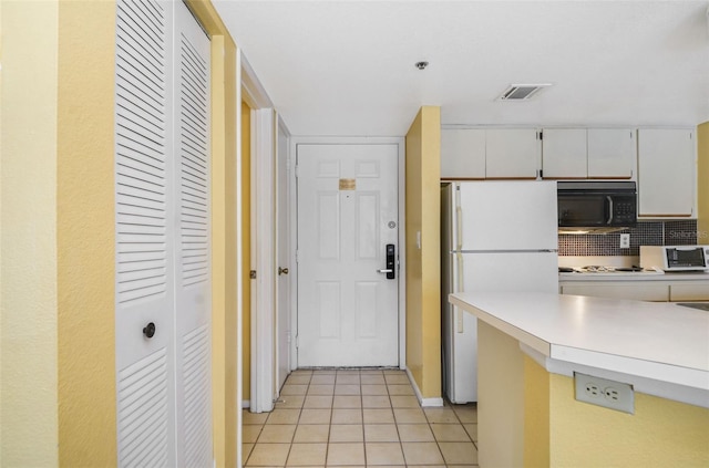 kitchen featuring white cabinets, decorative backsplash, light tile patterned flooring, and white appliances