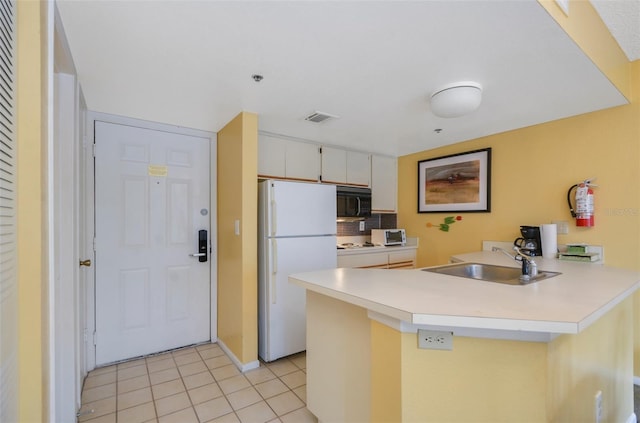 kitchen with sink, white cabinetry, white fridge, light tile patterned floors, and kitchen peninsula