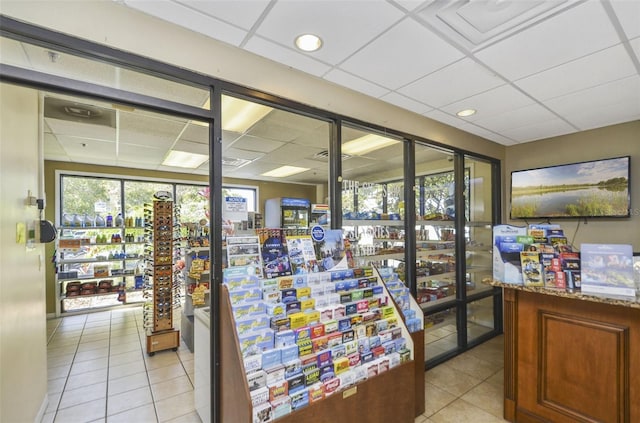 interior space featuring a paneled ceiling, stone counters, and light tile patterned flooring