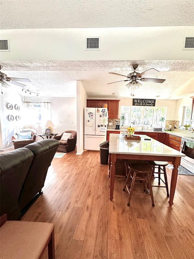 dining space with ceiling fan, a textured ceiling, and light hardwood / wood-style flooring