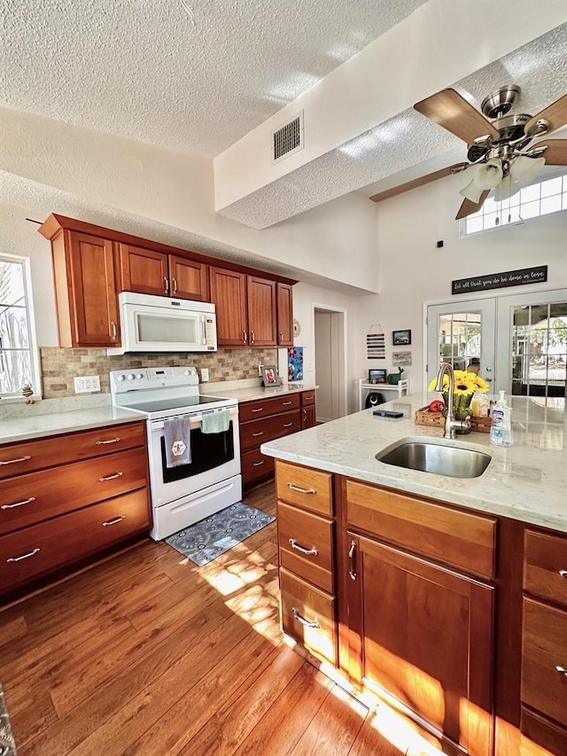 kitchen with white appliances, sink, decorative backsplash, plenty of natural light, and light hardwood / wood-style floors