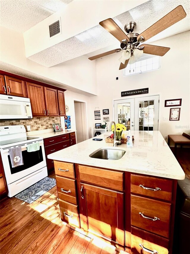 kitchen with sink, french doors, light stone counters, backsplash, and white appliances