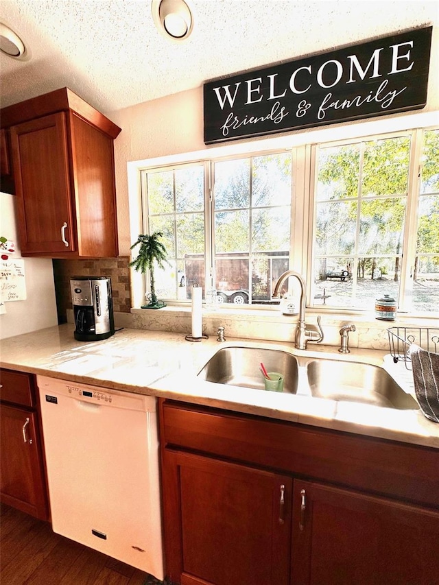 kitchen featuring dishwasher, dark wood-type flooring, sink, light stone countertops, and a textured ceiling