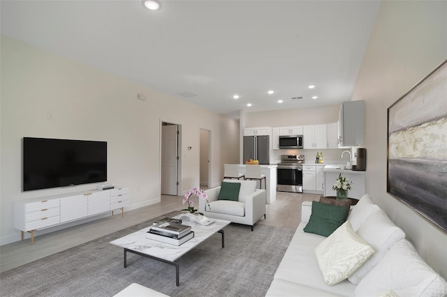 living room featuring sink and light hardwood / wood-style flooring