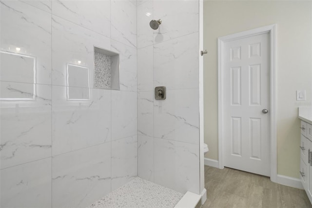 bathroom with vanity, toilet, and tiled shower