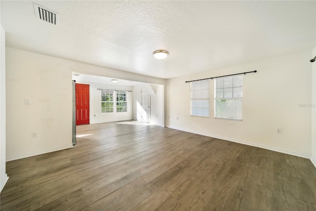 unfurnished living room featuring dark hardwood / wood-style flooring and a textured ceiling