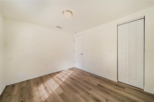 unfurnished bedroom featuring a closet and hardwood / wood-style flooring