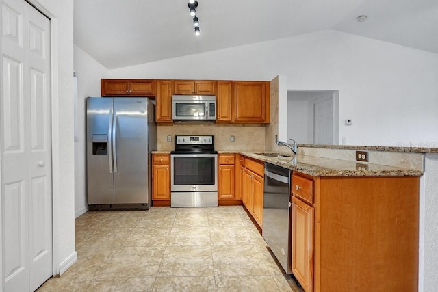 kitchen with light stone countertops, sink, kitchen peninsula, lofted ceiling, and appliances with stainless steel finishes