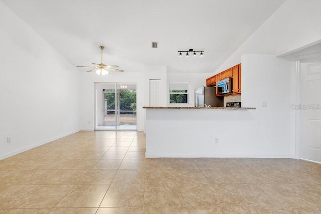 unfurnished living room featuring ceiling fan, light tile patterned floors, and vaulted ceiling