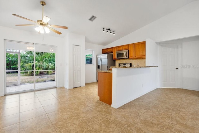 kitchen featuring light stone countertops, ceiling fan, stainless steel appliances, kitchen peninsula, and vaulted ceiling