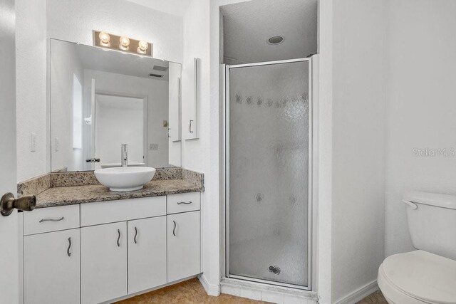 bathroom featuring vanity, a shower with shower door, and toilet