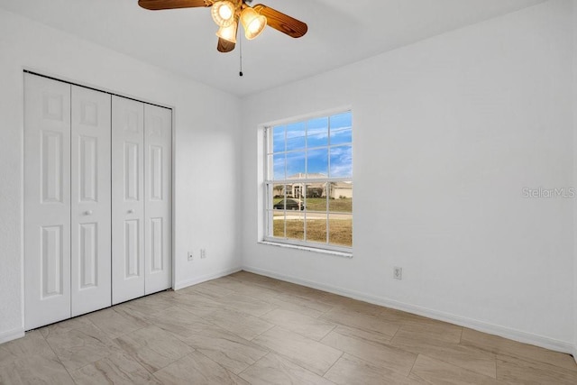 unfurnished bedroom with ceiling fan and a closet