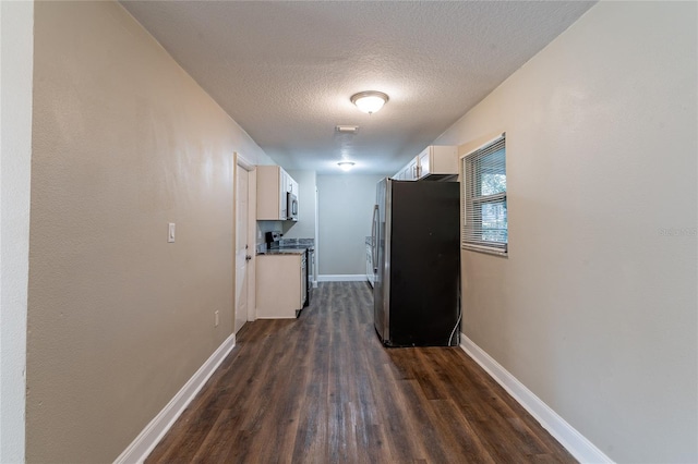 hallway with a textured ceiling and dark wood-type flooring