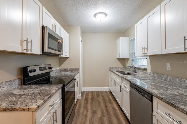 kitchen featuring white cabinetry, appliances with stainless steel finishes, dark hardwood / wood-style floors, dark stone countertops, and a textured ceiling